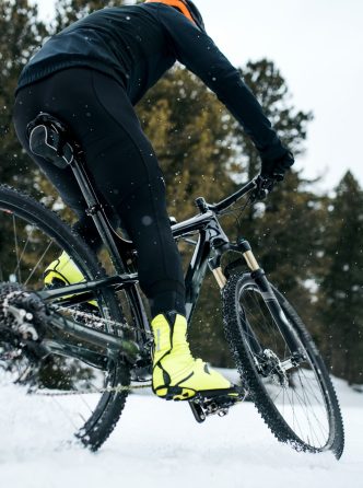 Midsection of mountain biker riding in snow outdoors in winter