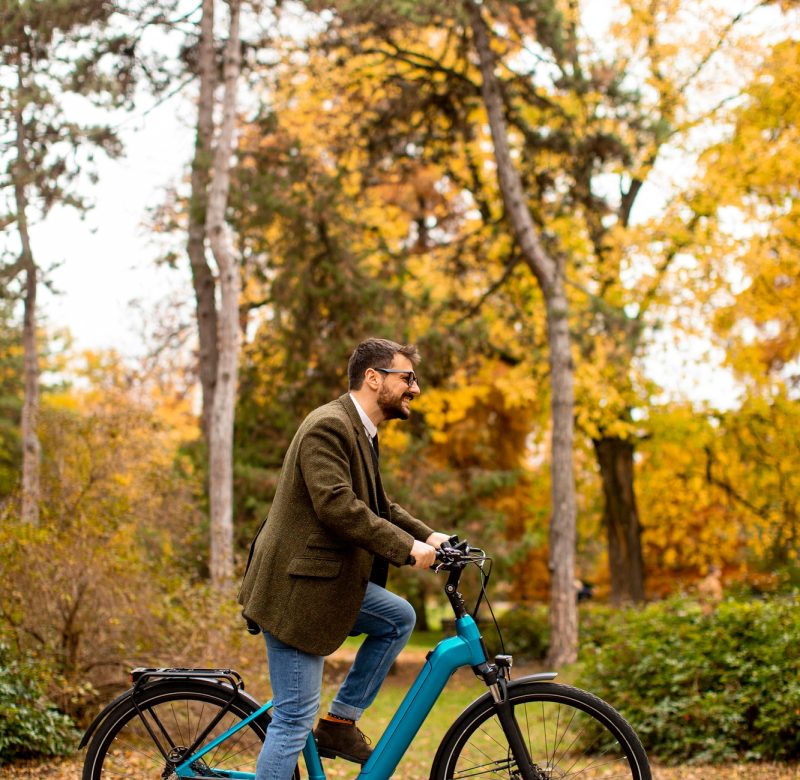Young man with electric bicycle in the autumn park